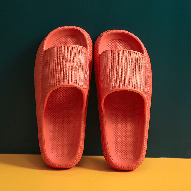 Pair of red slippers on a yellow surface with a dark green background