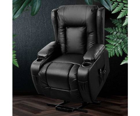 Black leather recliner chair with cup holders against a dark wall with green foliage