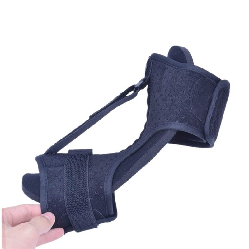 Black foot orthosis brace held by a hand on a white background