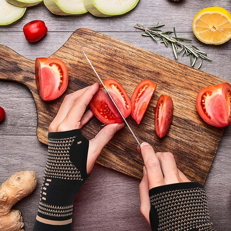 Person slicing tomatoes on a wooden cutting board with various vegetables around.