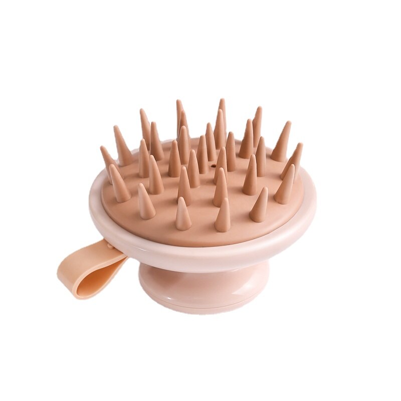 Pink scalp massager with pointed projections on a white background